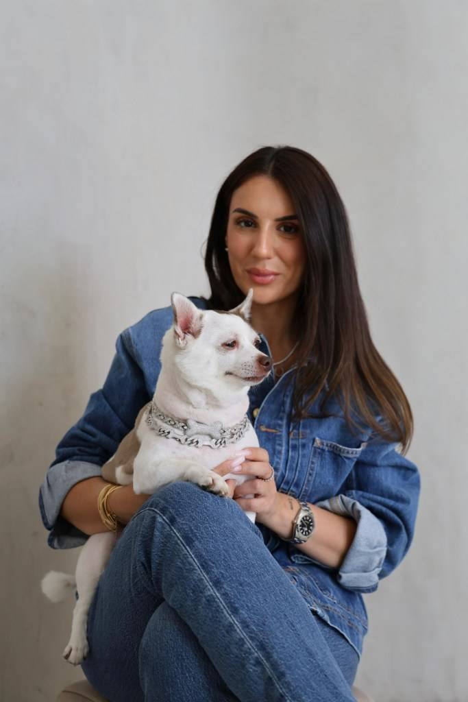 Racheli Shamir Waters holding her dog wearing a diamond collar.