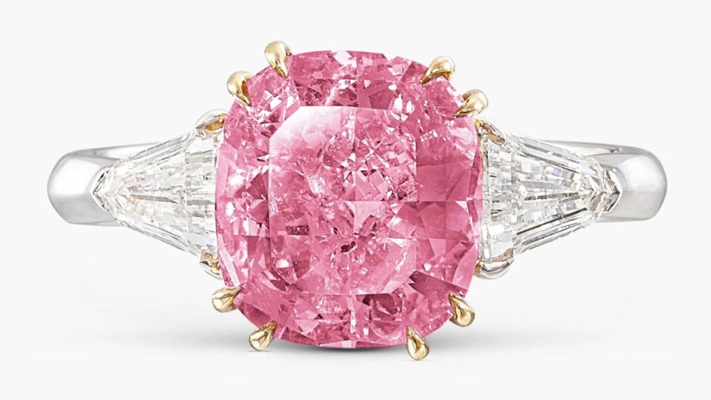 A ring with a cushion-shaped, 2.86-carat, fancy-vivid-purplish-pink, I2 diamond between two shield-shaped diamonds Sotheby's image