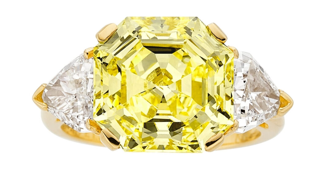 A Van Cleef & Arpels ring features a cut-cornered square step-cut, 6.88-carat, fancy-intense-yellow, VS1 diamond between two calf’s head-cut diamonds at Heritage Auctions image