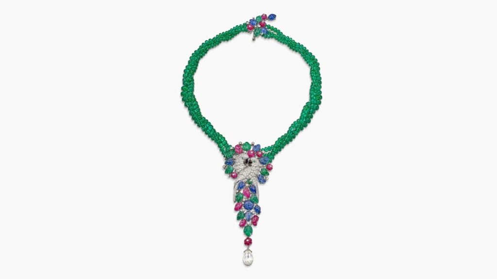 A Cartier tutti frutti pendant necklace designed as a pair of embracing parrots. It comprises brilliant-cut diamonds, emeralds, sapphires, rubies, and mother of pearl, and suspends a diamond briolette by Sotheby's image